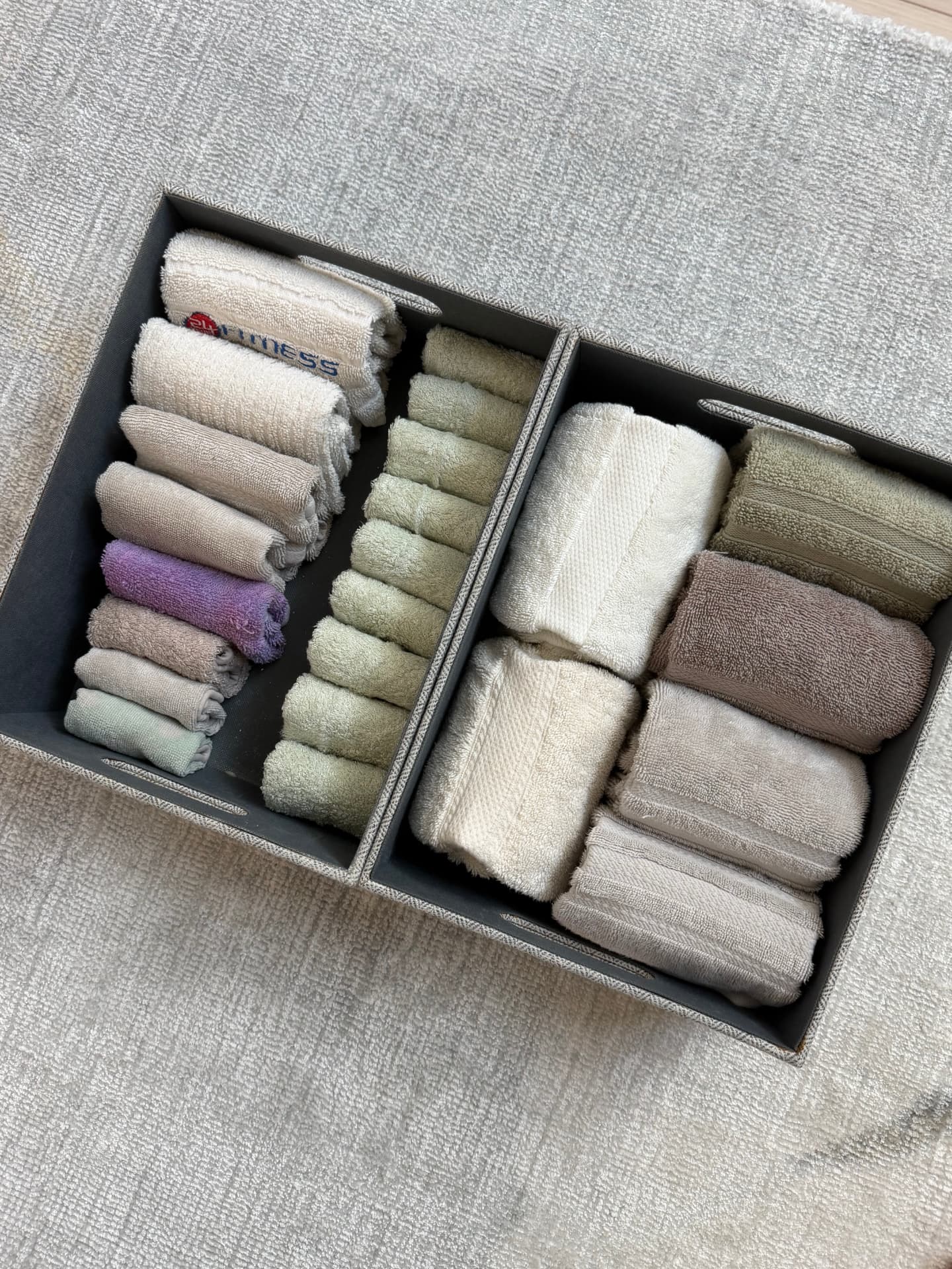 Basket of rolled washcloths and hand towels sorted by size and color